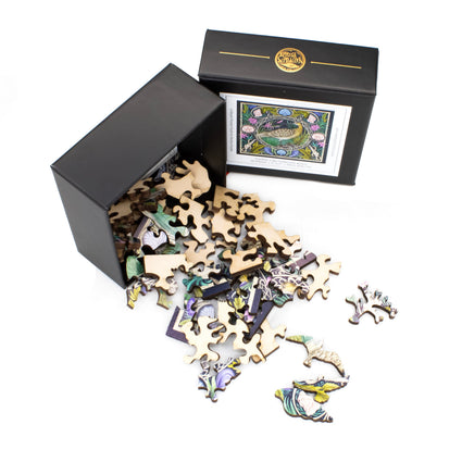 Mini Wooden Jigsaw Puzzle pieces spilling out of an elegant, black branded Nautilus Puzzles box.